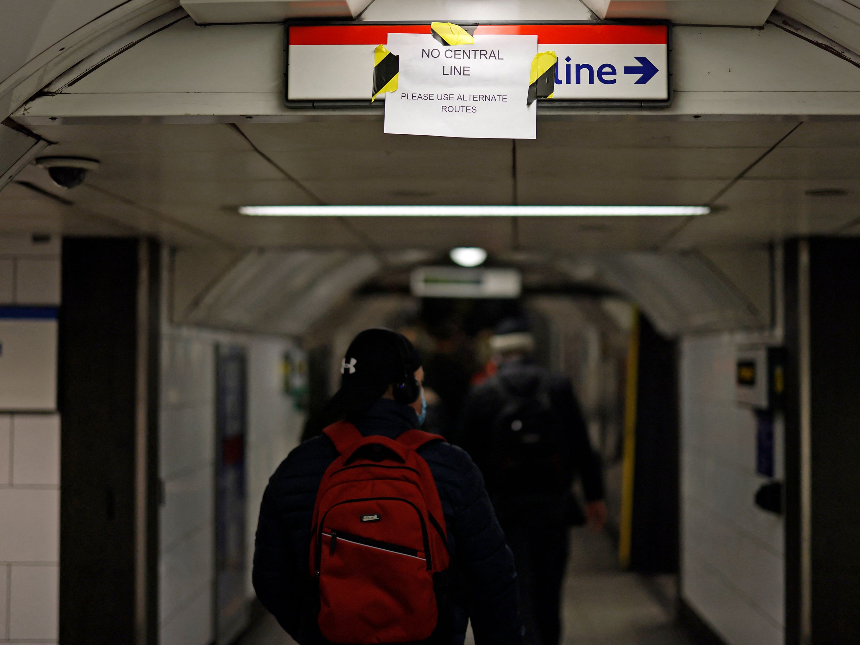 Commuters pass a hand-written note notifying commuters of disruptions to London Underground services due to strike action