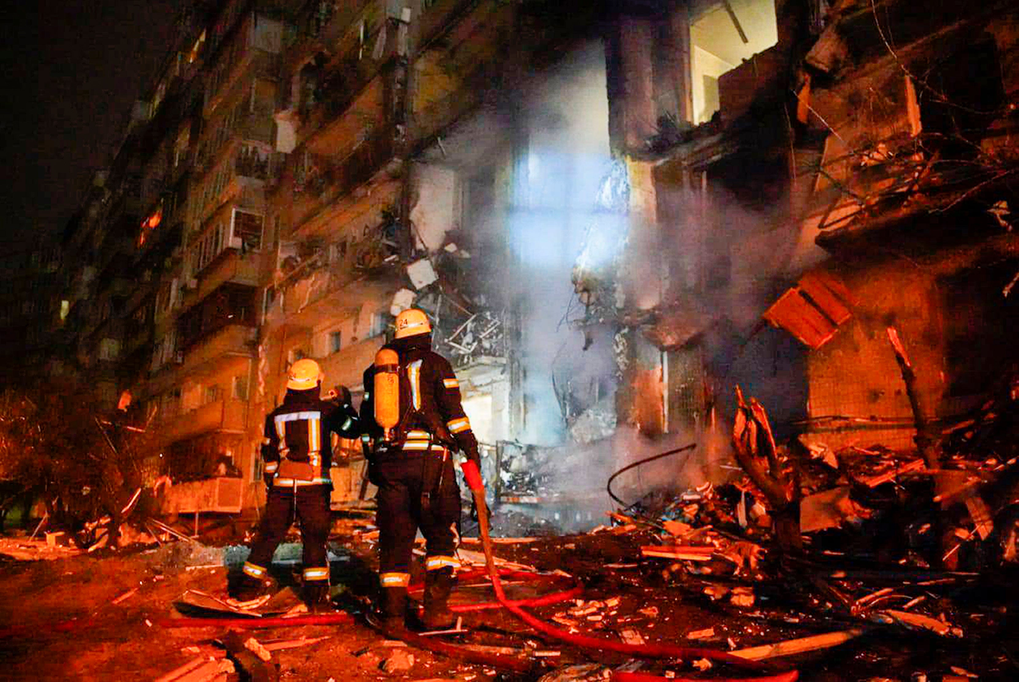 Firefighters inspect the damage at a building following a rocket attack in Kyiv on Friday