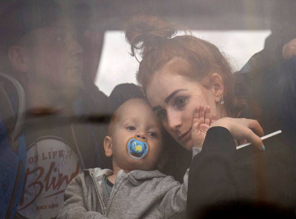 A woman holds her baby inside a bus as they leave Kyiv, Ukraine (Emilio Morenatti/AP)
