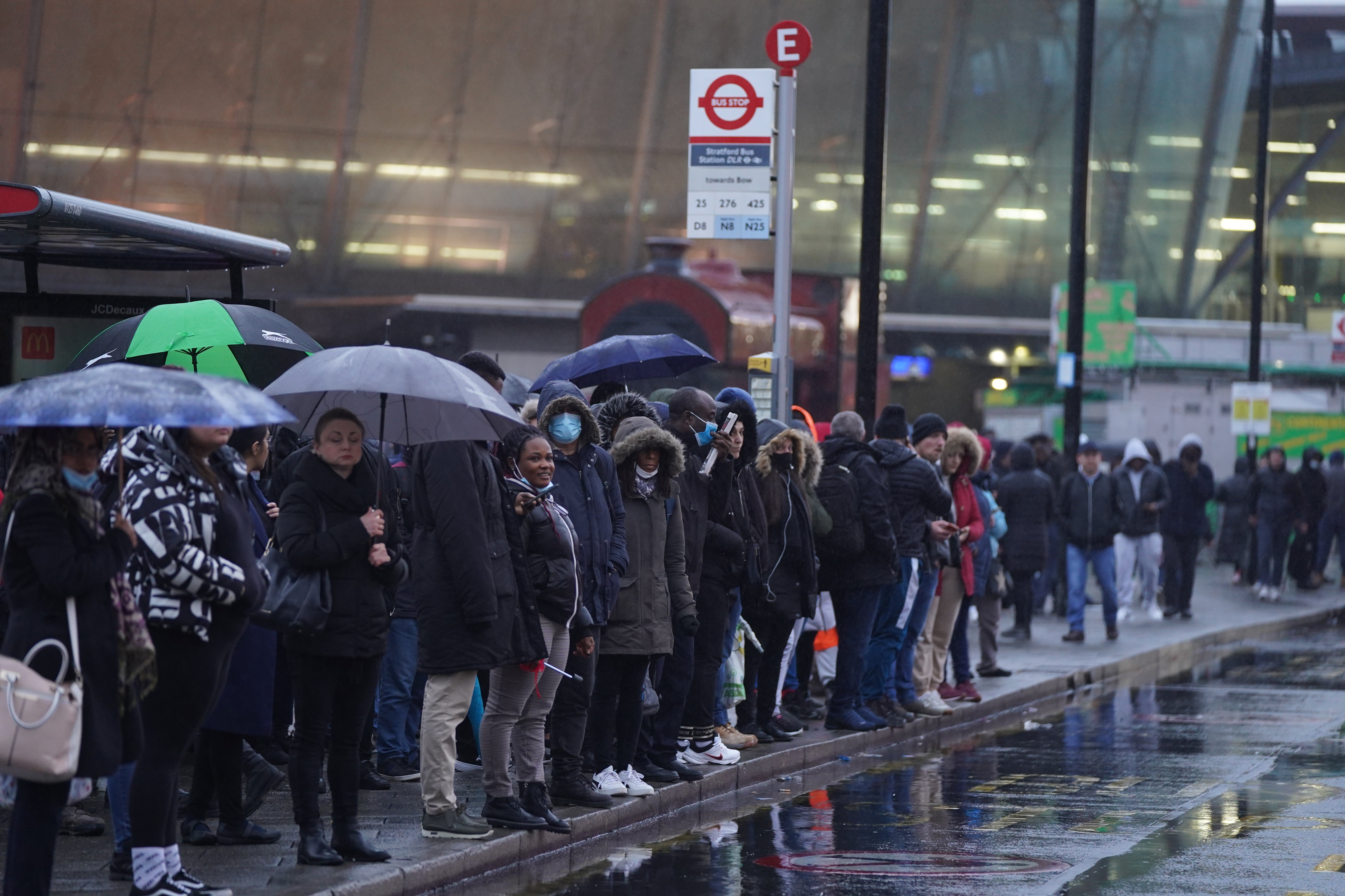 Commuters queue for buses in the rain in east London (Stefan Rousseau/PA)
