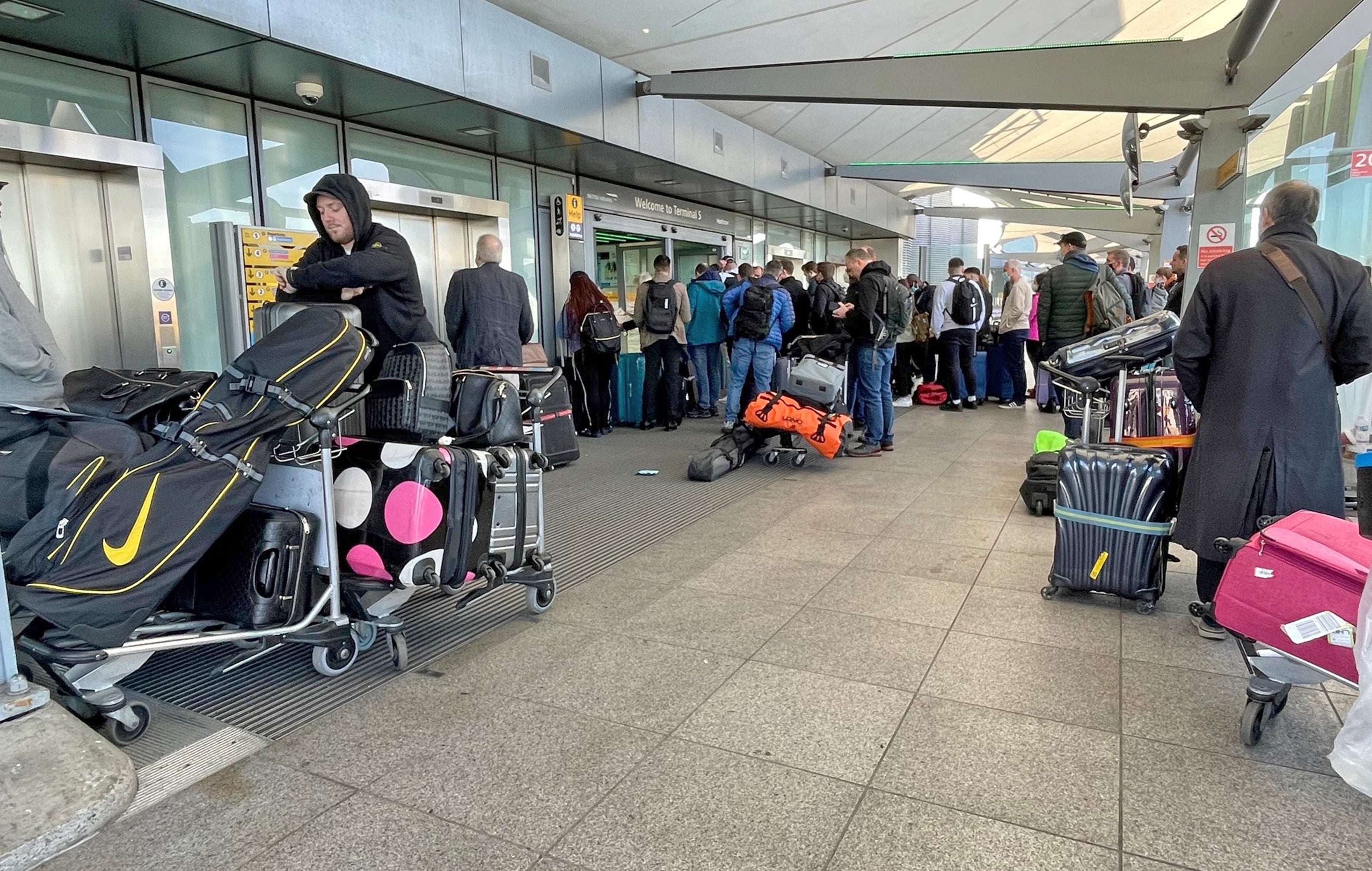 Passengers queue at the Arrivals entrance of Heathrow Airport T5