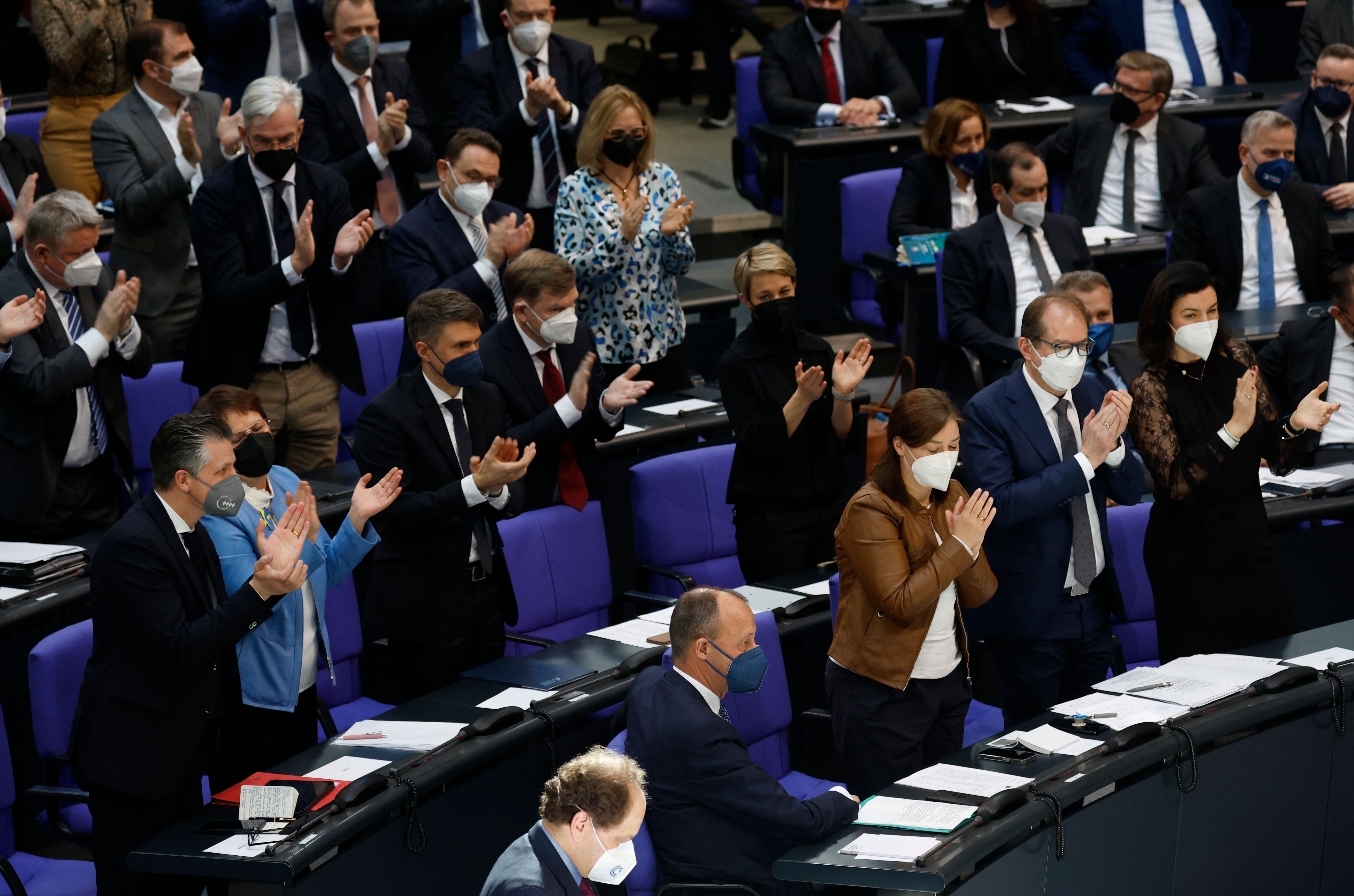 German lawmakers applaud an extraordinary session of the Bundestag on Sunday