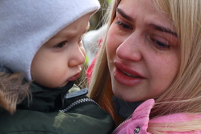 <p>A mother in tears with her child after fleeing from Ukraine near the border checkpoint at Korczowa, Poland on Tuesday</p>
