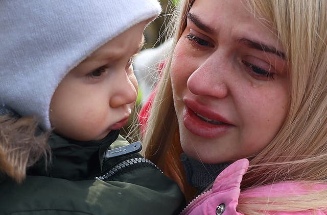<p>A mother in tears with her child after fleeing from Ukraine near the border checkpoint at Korczowa, Poland on Tuesday</p>