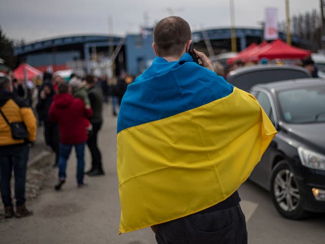 Un hombre envuelto en la bandera ucraniana en el cruce fronterizo con Eslovaquia mientras los refugiados huyen del conflicto.