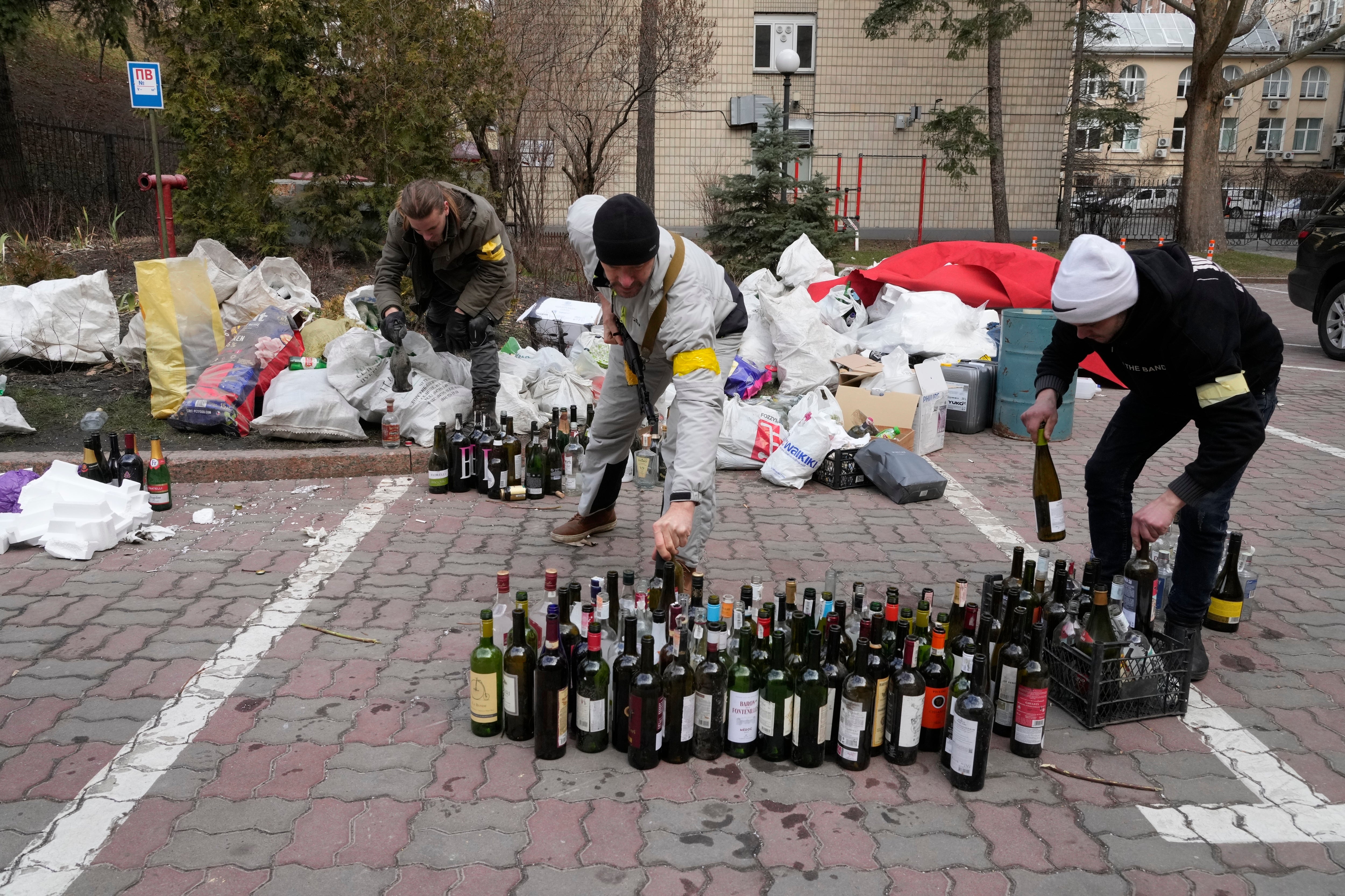 Members of civil defence prepare Molotov cocktail in a yard in Kyiv, Ukraine