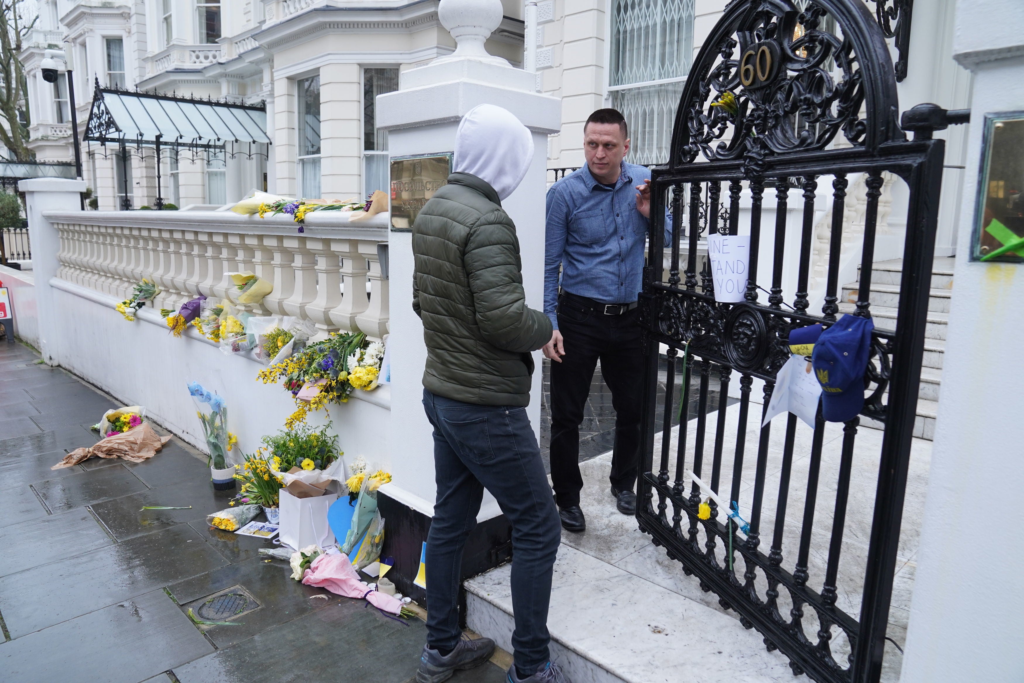 An embassy staff member talks to a man who arrived to sign up to join the Ukrainian armed forces outside the Ukrainian Embassy