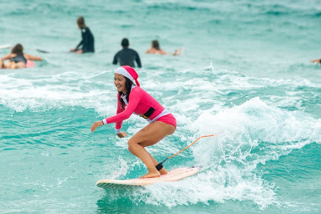 <p>A woman in a Santa outfit surfs at Bondi Beach on Christmas Day</p>
