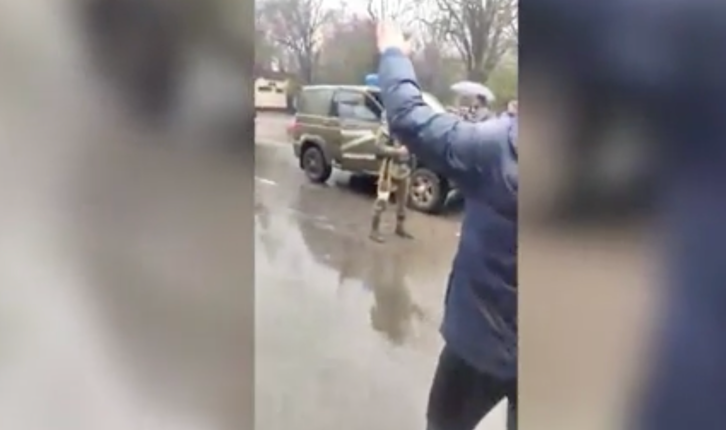 A Russian army soldier confronts the crowd and shoots in the air