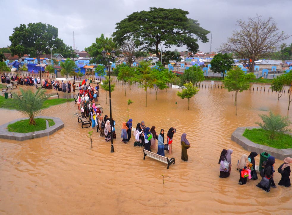 <p>People wade floodwaters as they evacuate after floods in Serang, Banten province on March 1, 2022</p>