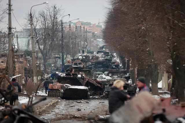 <p>People look at the gutted remains of Russian military vehicles on a road in the town of Bucha, close to Ukraine’s capital Kyiv, on 1 March 2022</p>