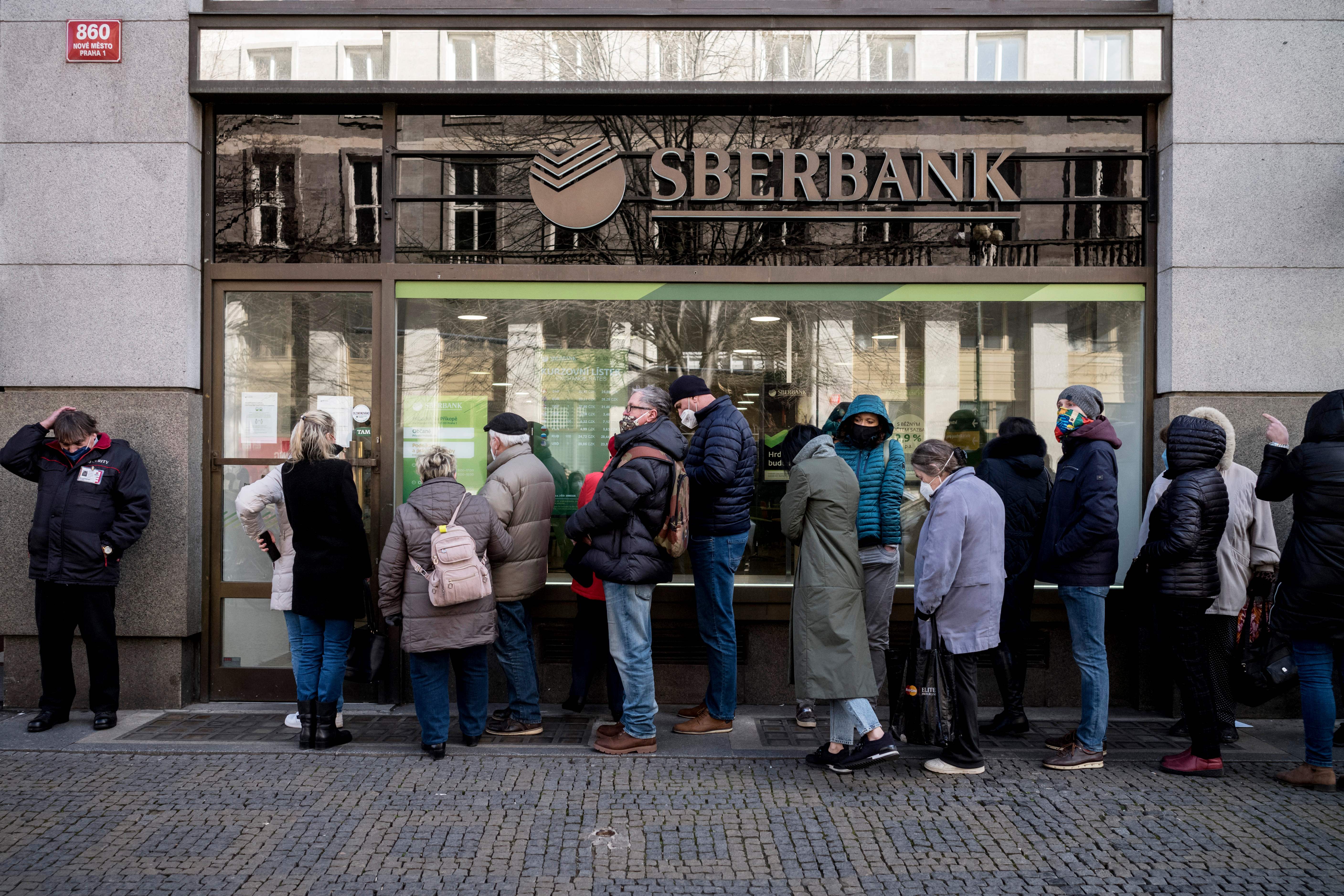 People queue outside a branch of Russian state-owned bank Sberbank to withdraw their savings and close their accounts in Prague on 25 February 2022, before Sberbank will close all its branches in the Czech Republic later in the day