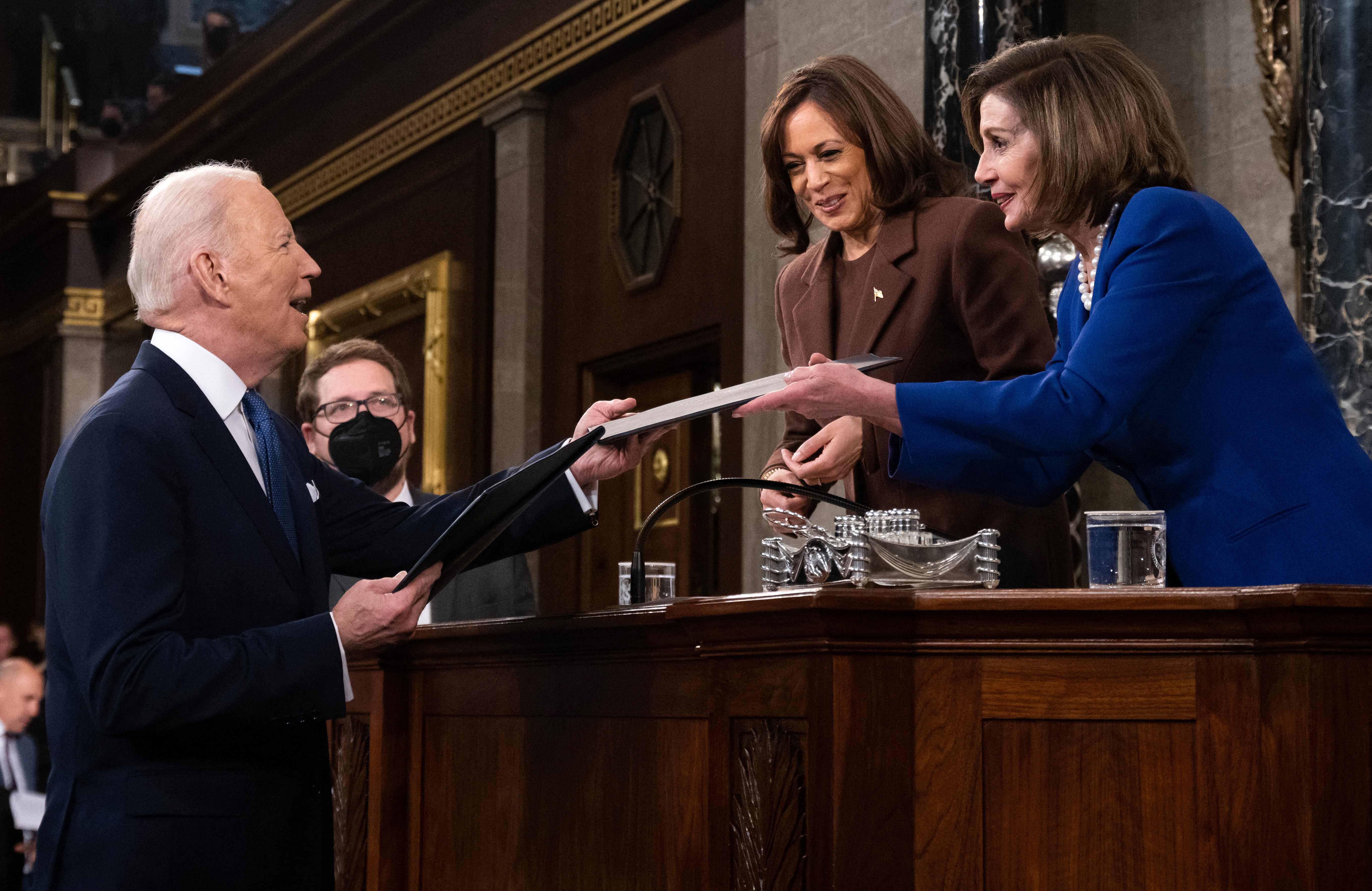 President Joe Biden hands a copy of his speech to US House Speaker Nancy Pelosi