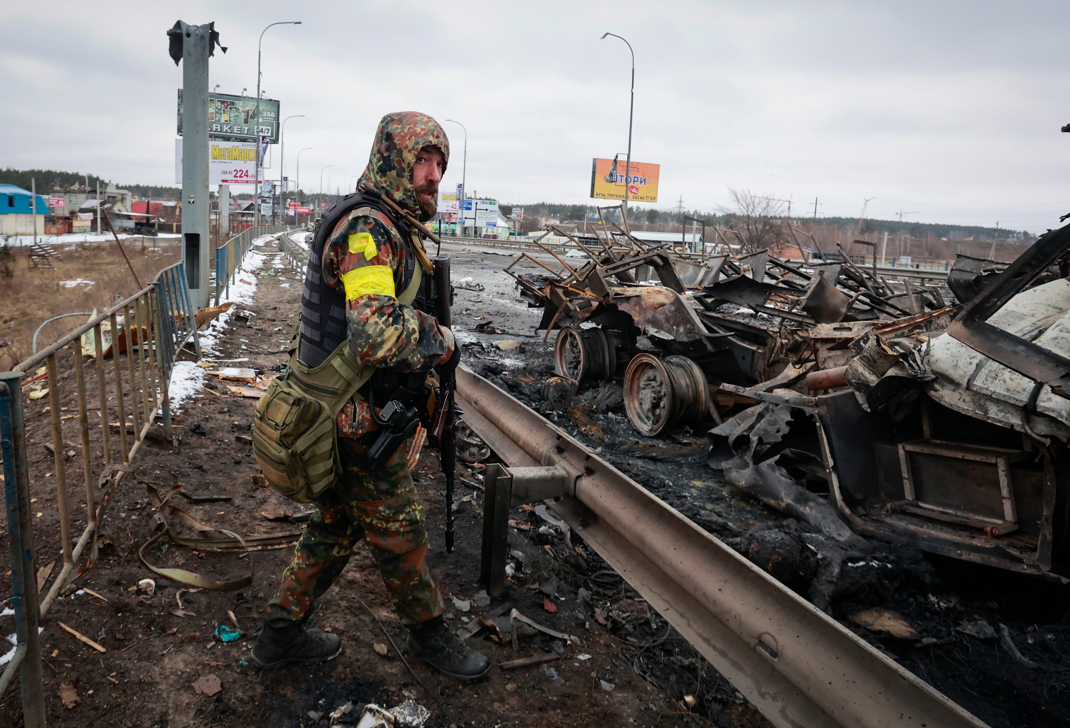 An armed man stands by the remains of a Russian military vehicle in Bucha, close to the capital Kyiv (Serhii Nuzhnenko/AP)