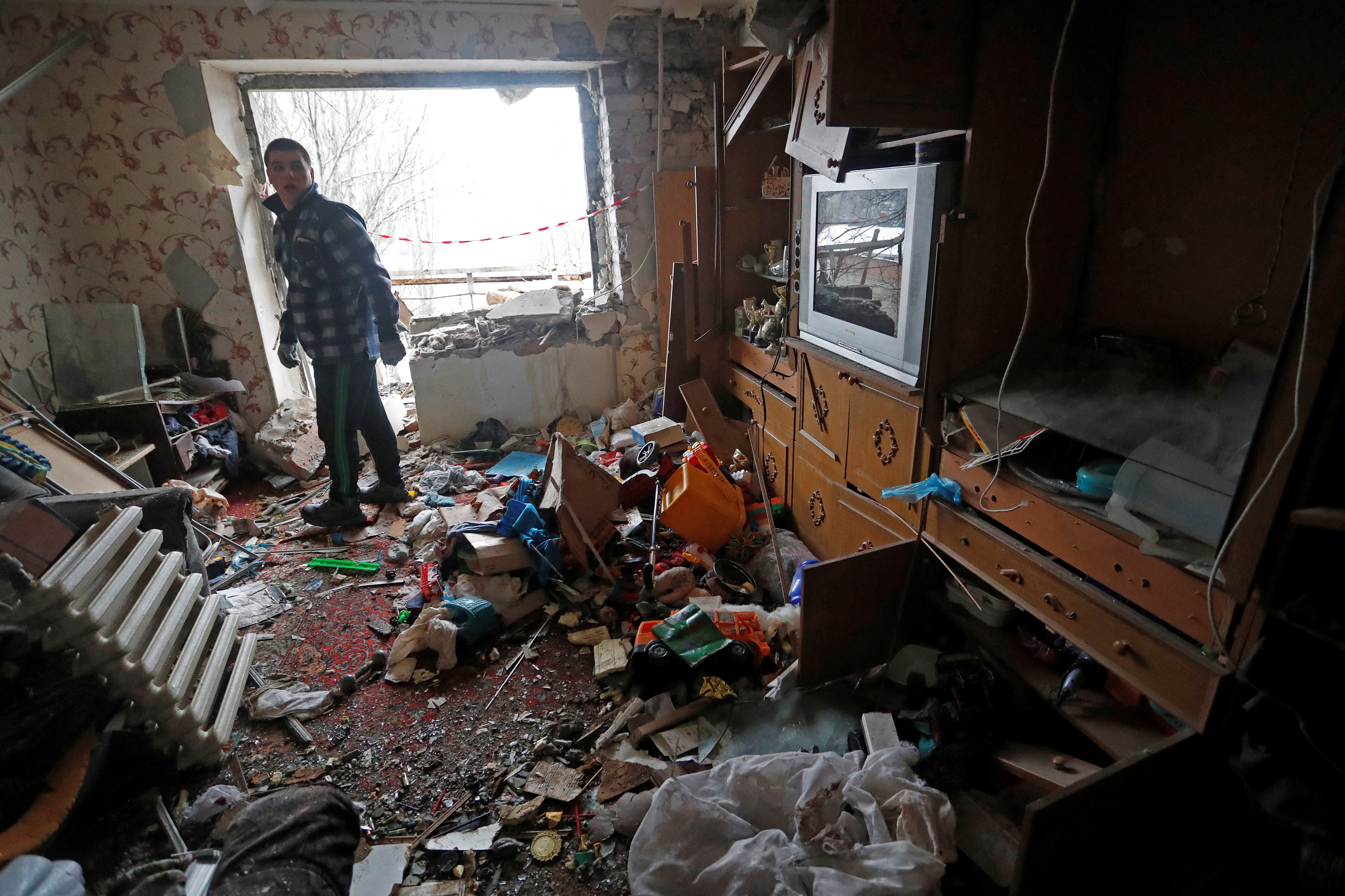 A man stands inside his apartment, which locals said was damaged by recent shelling, in the separatist-controlled town of Yasynuvata in the Donetsk region