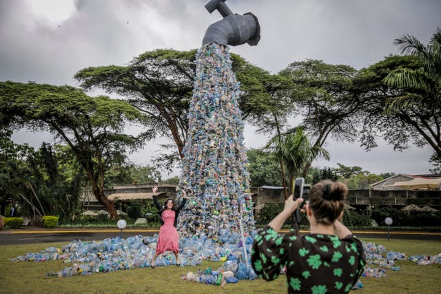 <p>Delegates take photos in front of a giant art sculpture showing a tap outpouring plastic bottles, each of which was picked up in the city’s Kibera neighborhood, during the UN Environment Assembly in Nairobi, Kenya</p>