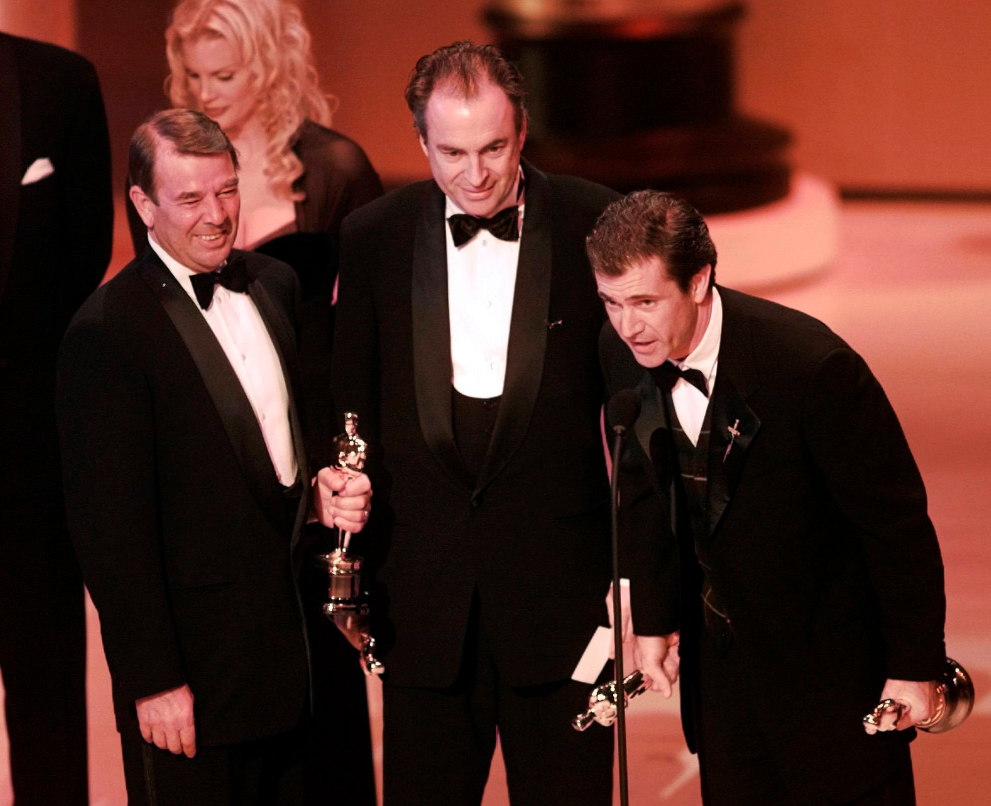 Mel Gibson, right, accepts the award for Best Picture for "Braveheart" at the 68th Annual Academy Awards in Los Angeles, Looking on are co-producers Alan Ladd Jr., left, and Bruce Davey