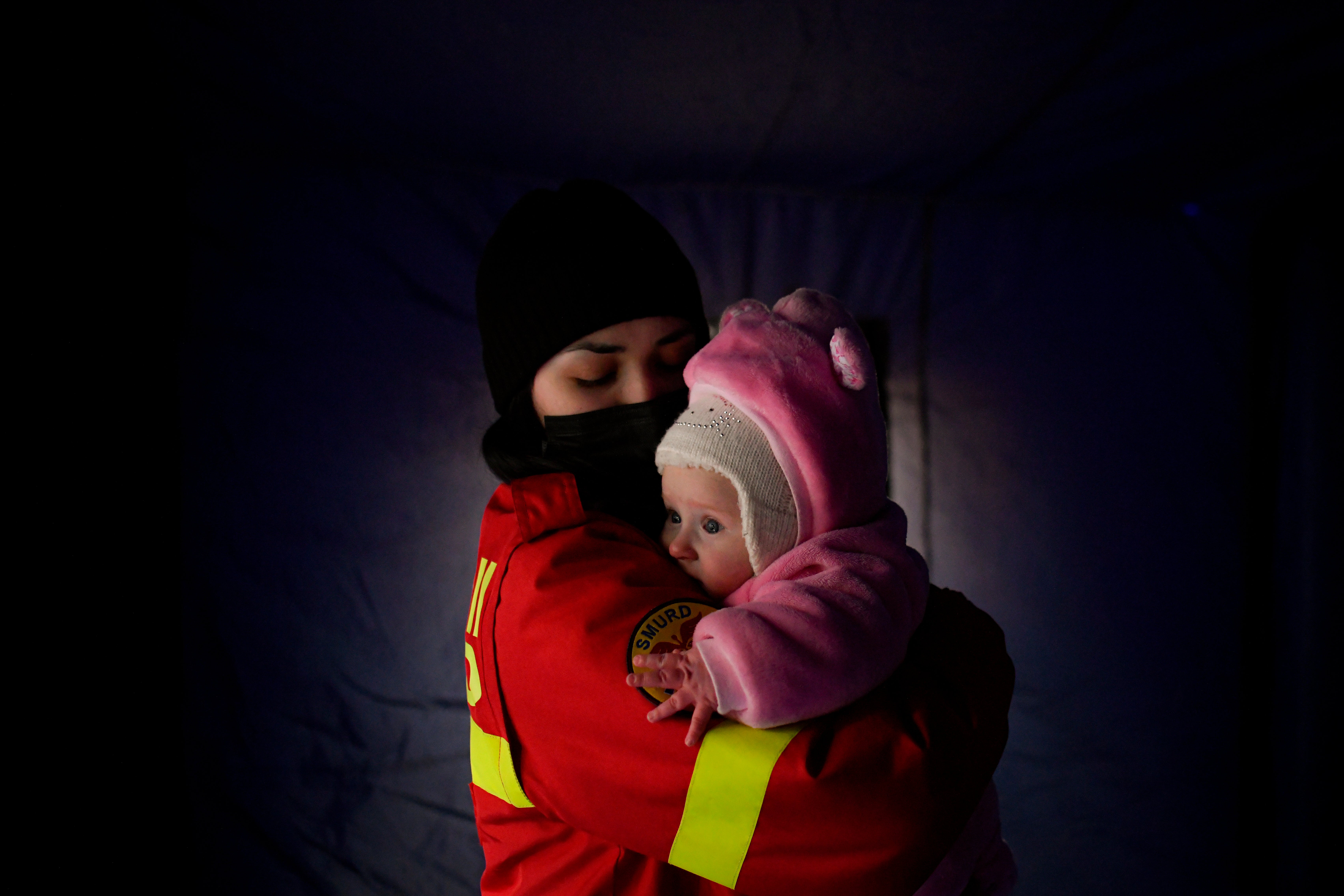 An employee from the Emergency Situation Inspectorate soothes the crying baby of a family fleeing the conflict from neighbouring Ukraine at the Romanian-Ukrainian border, in Siret, Romania (Andreea Alexandru/AP)