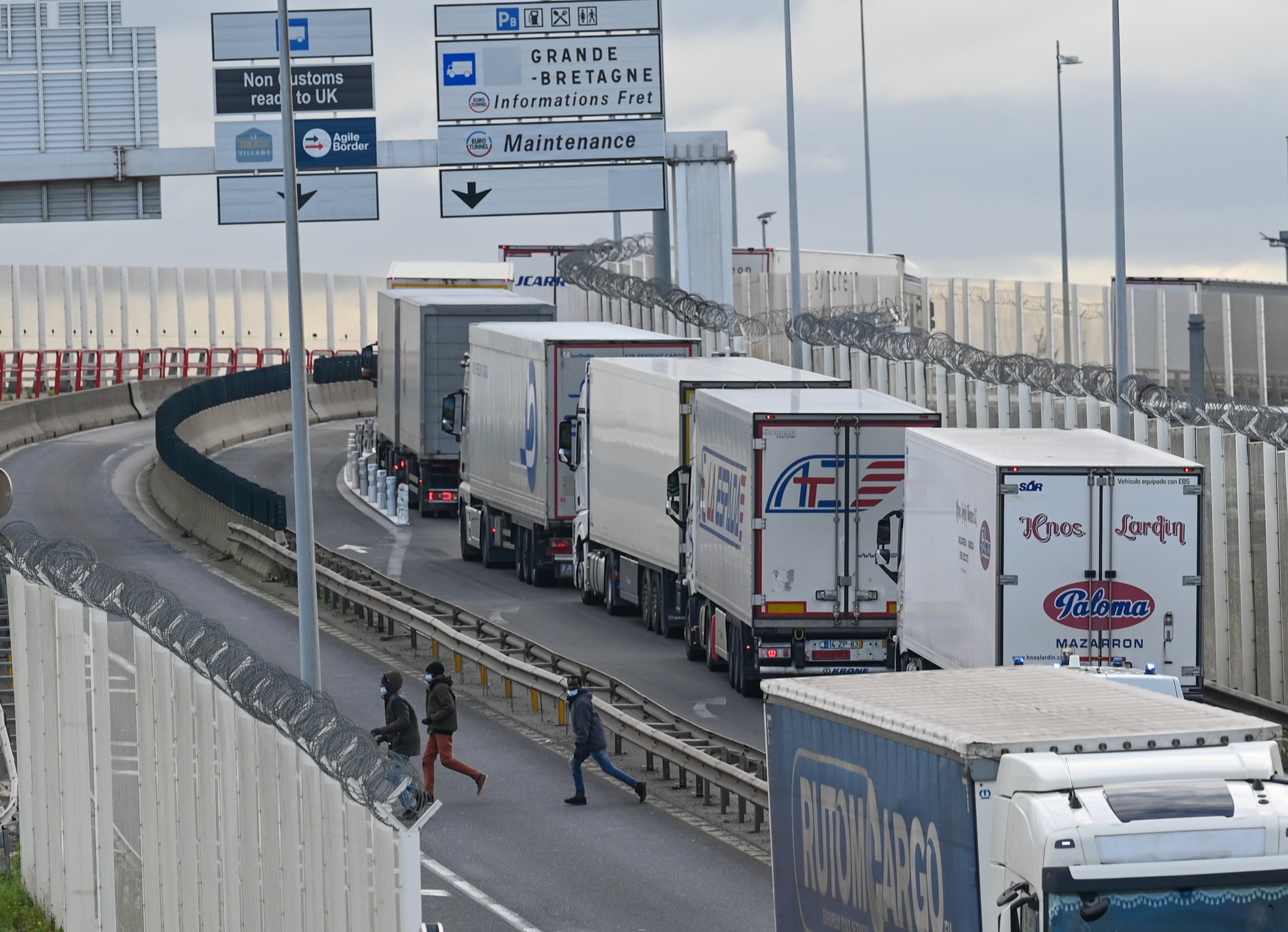 Migrants leave after attempting to climb into the back of lorries bound for Britain