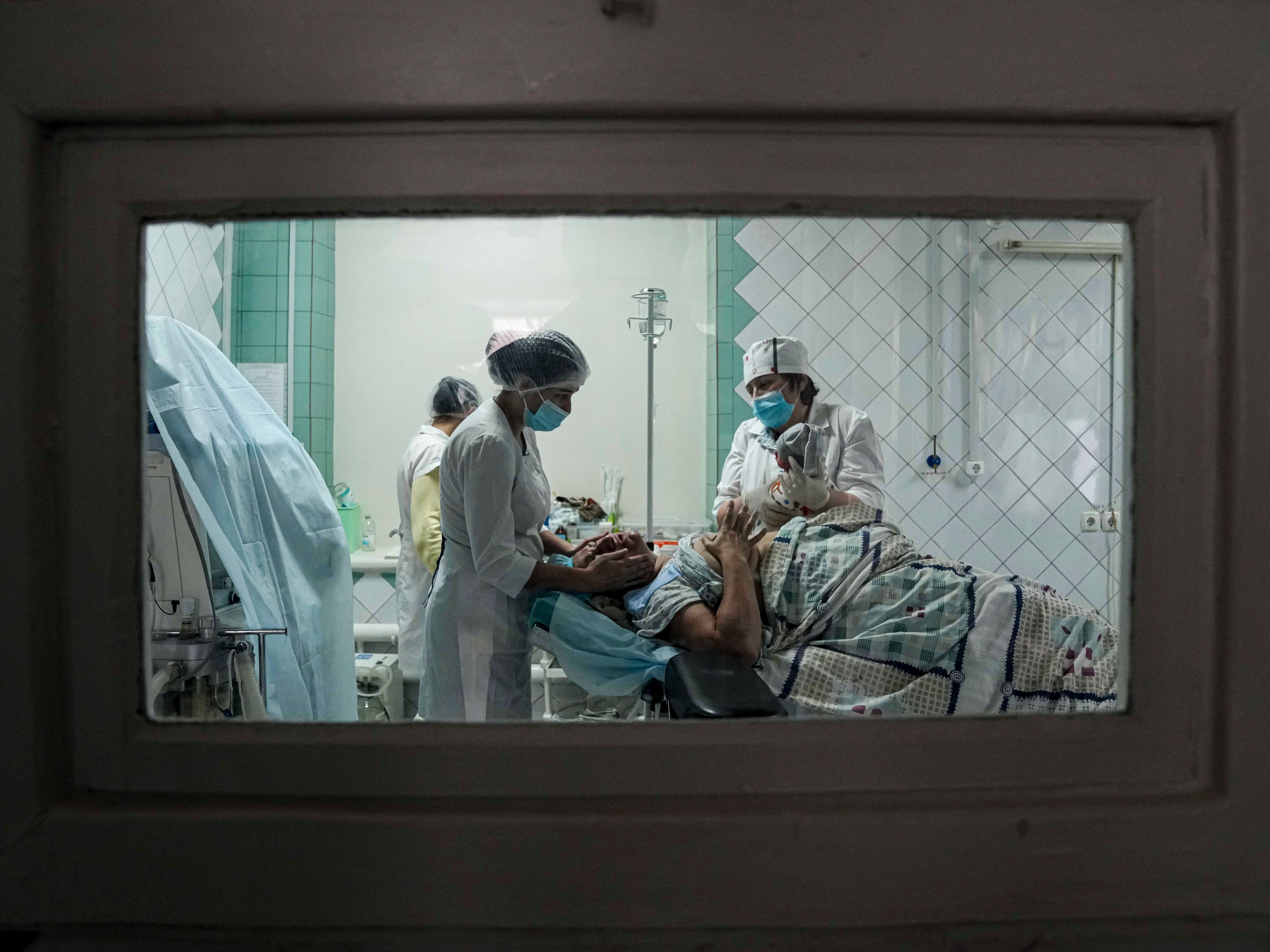 Medical workers show a newborn baby to a woman who gave birth in a maternity hospital basement converted into a medical ward in Mariupol, Ukraine