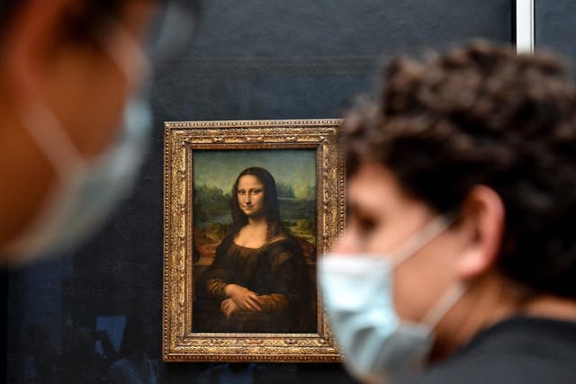 <p>In this photo taken on May 19, 2021 visitors walk past the painting "La Joconde" The Mona Lisa by Italian artist Leonardo Da Vinci on display in the "Salle des Etats" at The Louvre Museum in Paris</p>