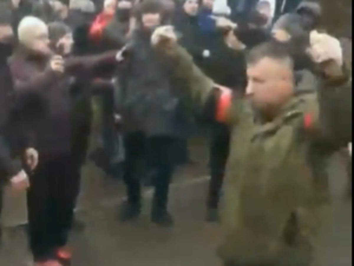 Russian soldier holding two grenades walks through Ukrainian crowd demanding they surrender