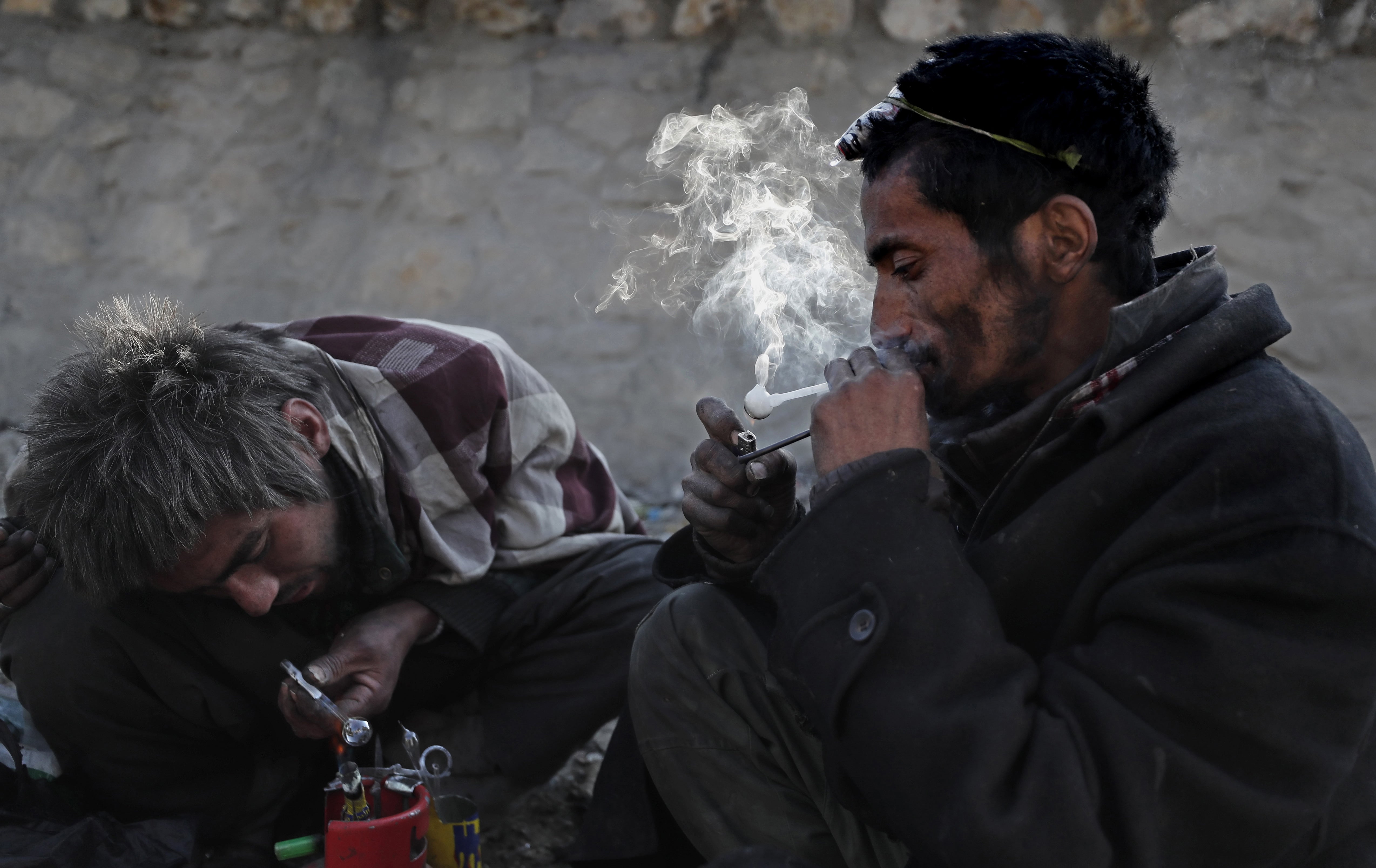 Afghan men addicted to heroin and methamphetamine take drugs in Kabul