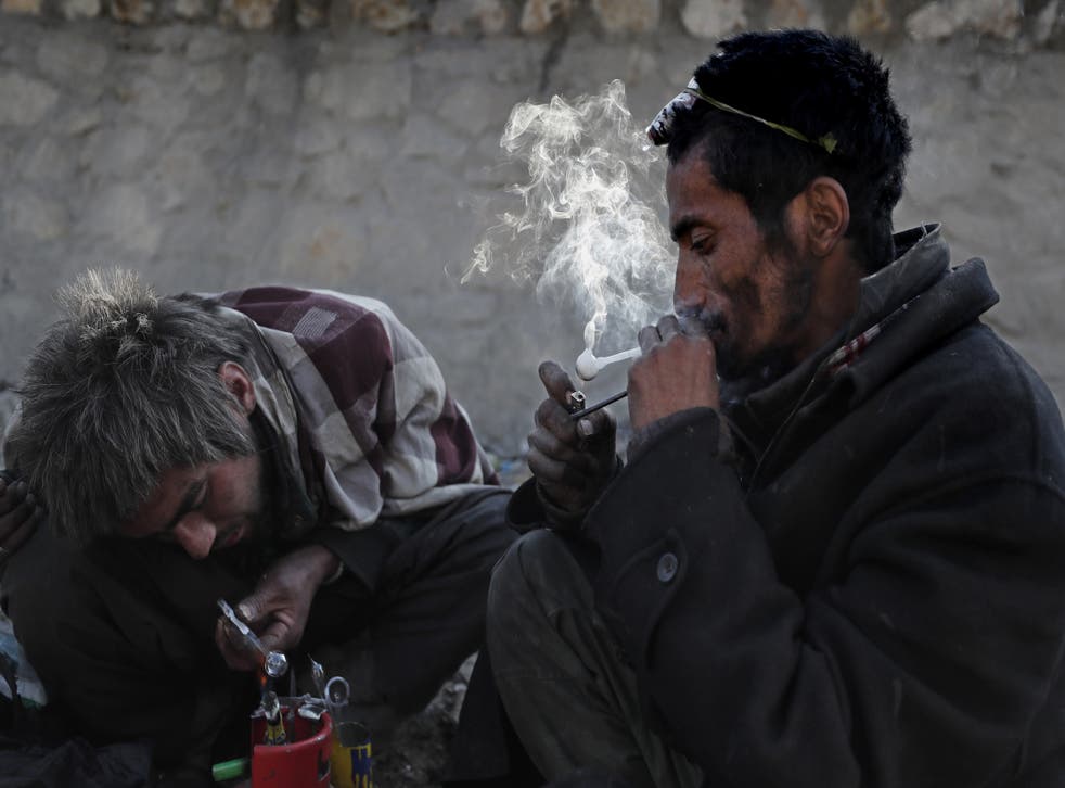 <p>Afghan men addicted to heroin and methamphetamine take drugs in Kabul</p>