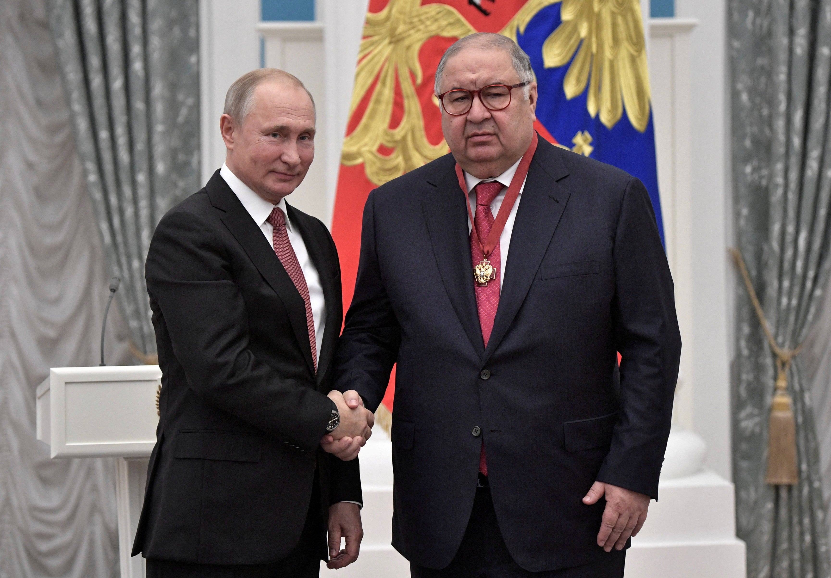 ussian President Vladimir Putin (L) shakes hands with Russian businessman and founder of USM Holdings Alisher Usmanov.