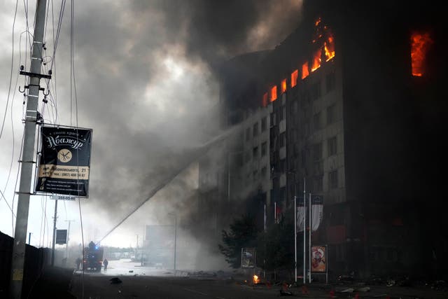 <p>Firefighters hose down a burning building after bombing in Kyiv on 3 March</p>