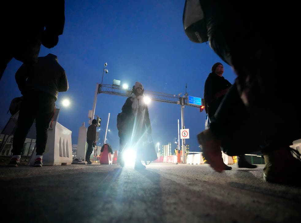 Displaced persons carry luggage as they arrive at a border crossing in Medyka, Poland (Markus Schreiber/AP)