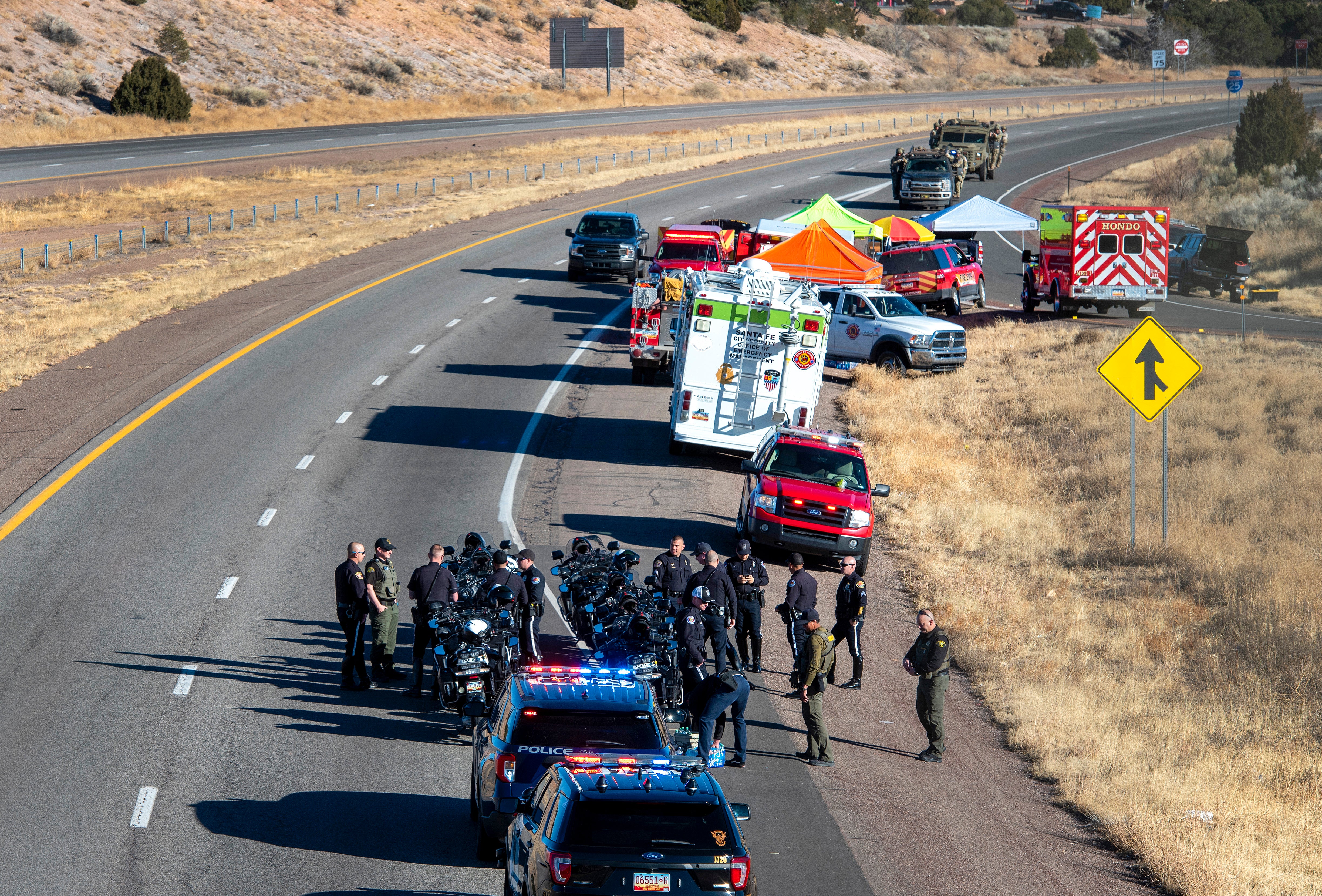 Law enforcement gathers along Interstate 25 as several agencies take part in a search for a suspect who was involved in a kidnaping and high speed chase that resulted in a Santa Fe Police Officer being killed