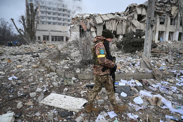 <p>A Ukrainian service member walks near a school building destroyed by shelling</p>