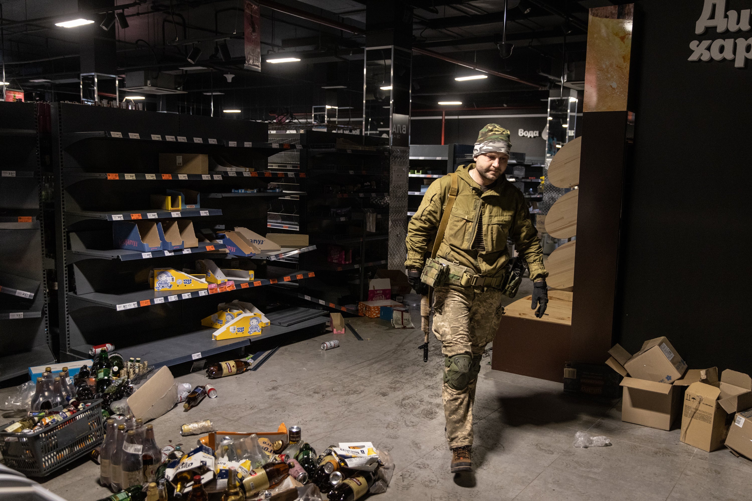 A Ukrainian military serviceman walks past empty shelves to collect food and other items to distribute to residents