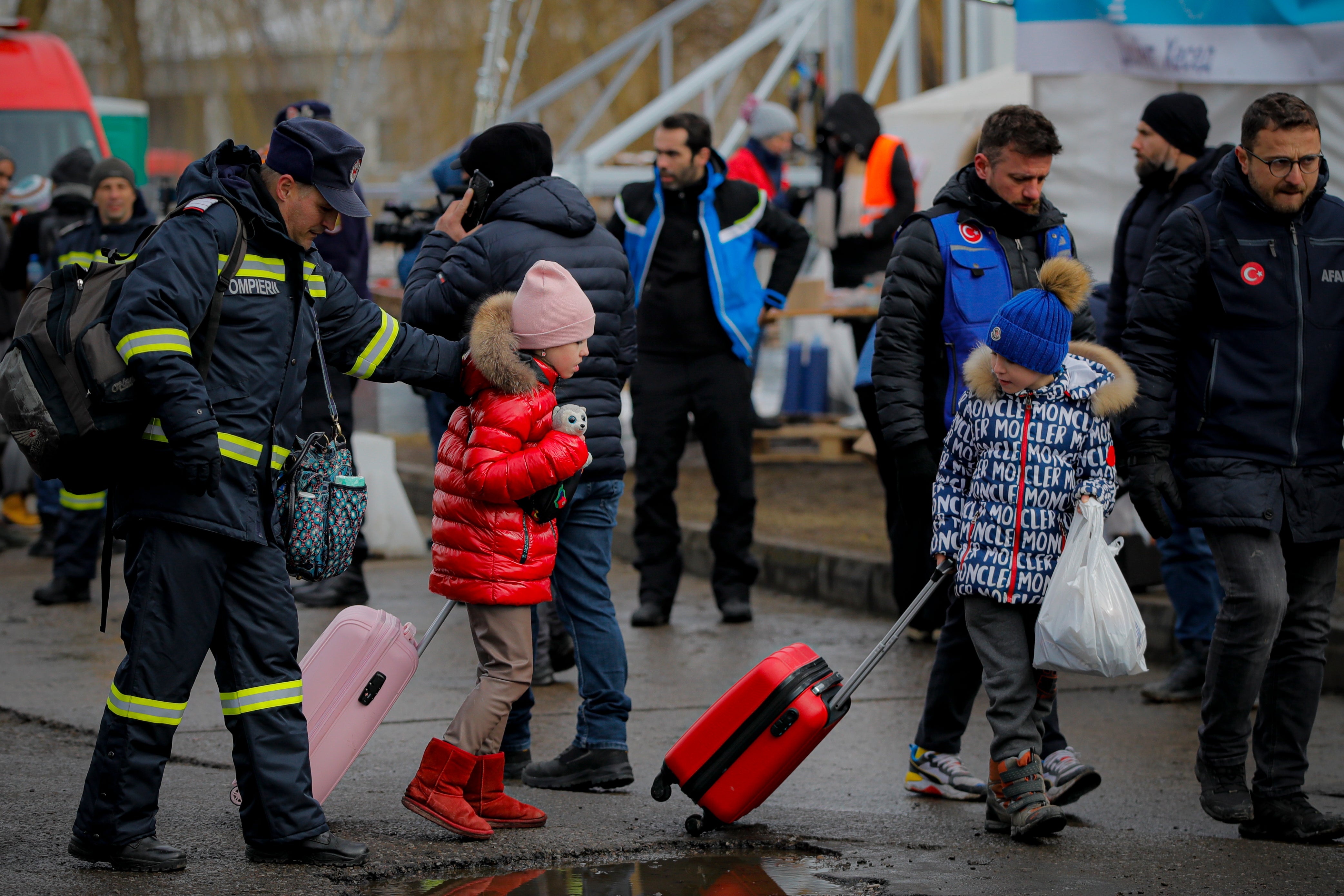 A firefighter helps refugees at the Romanian-Ukrainian border, in Siret, Romania