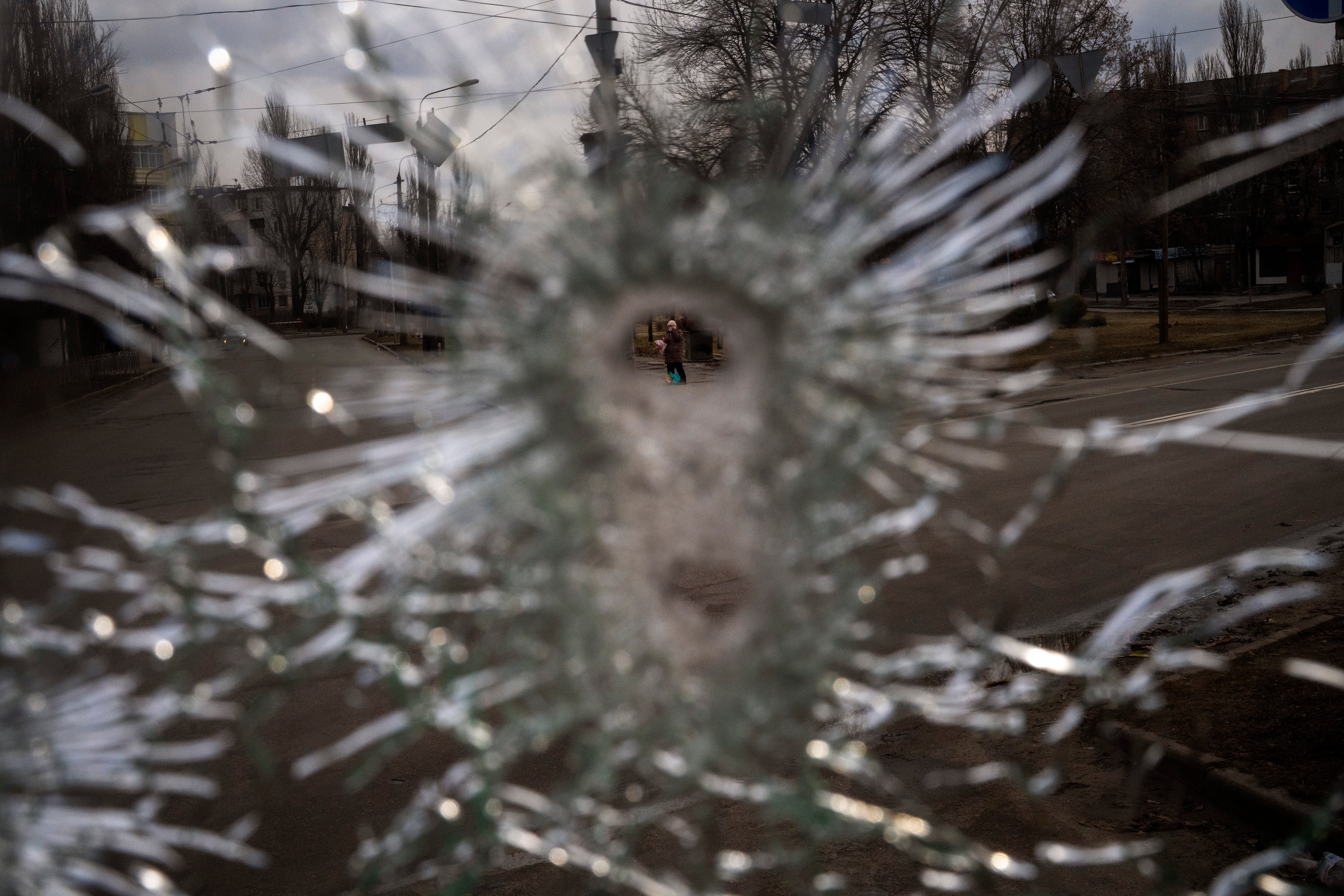 A man is seen through a bullet hole of a machine-gunned bus after an ambush in the city of Kyiv, Ukraine, Friday, March 4, 2022