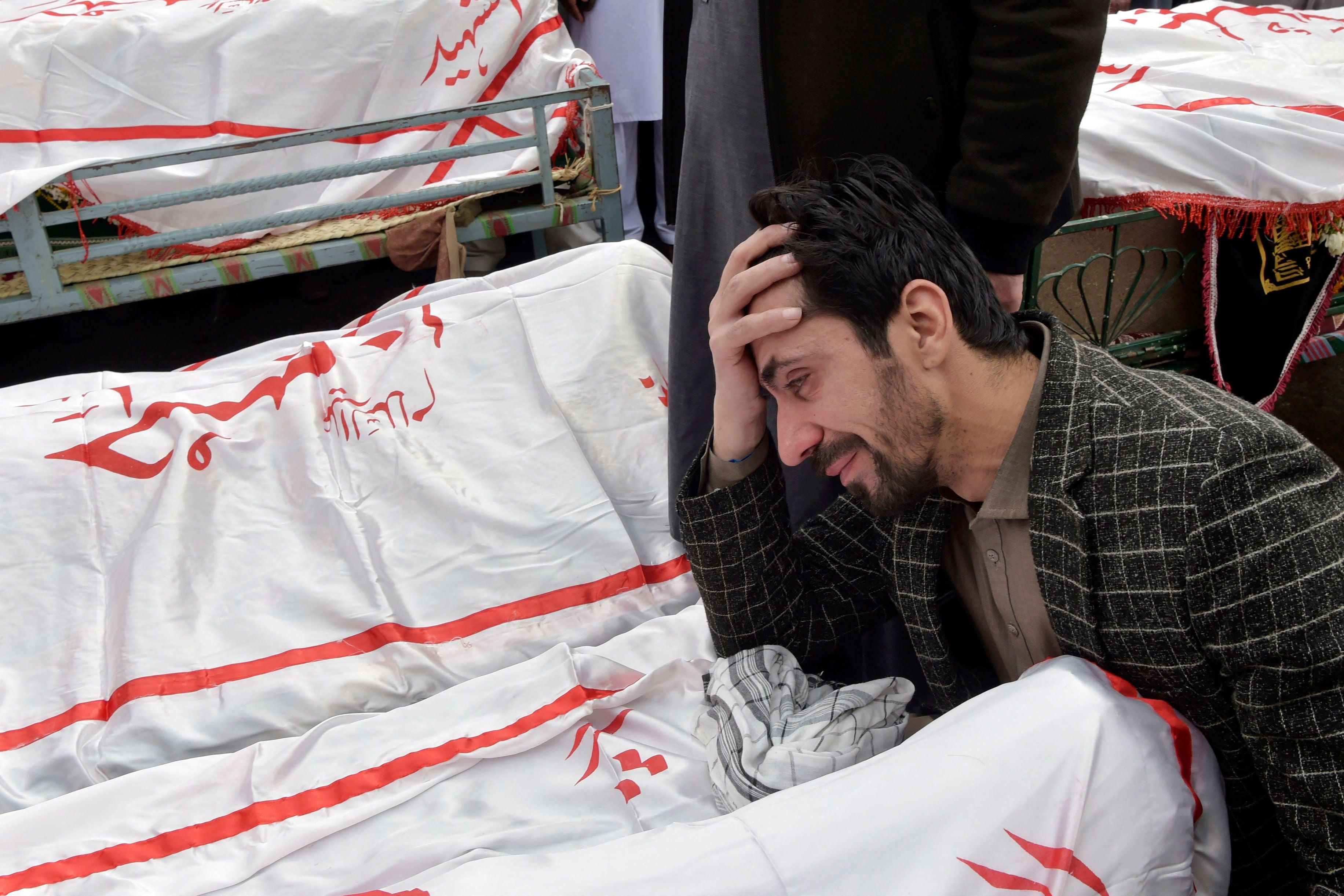A man mourns next to the body of his relative who died in a bomb blast in Pakistan