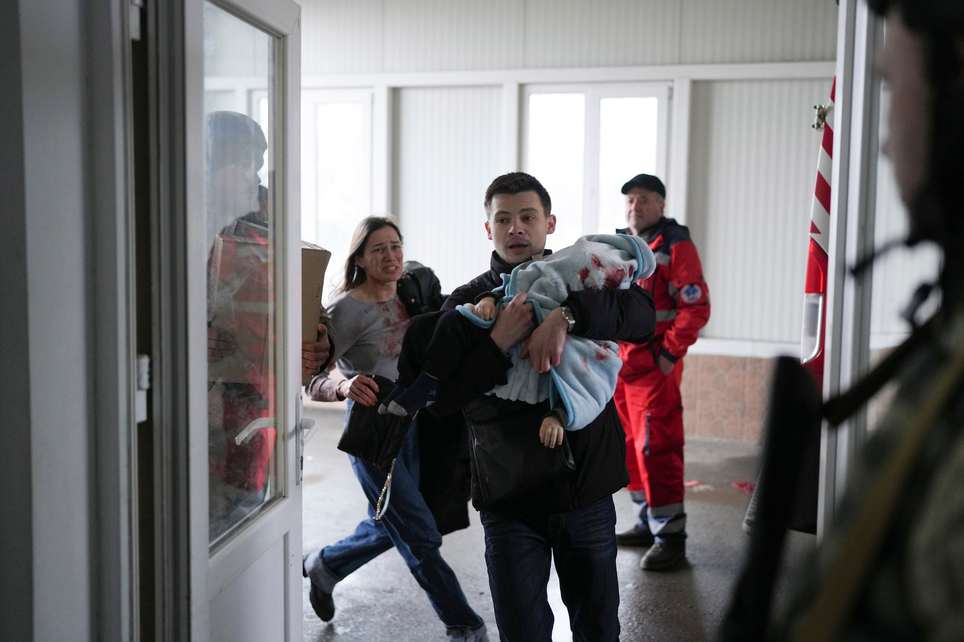 Marina Yatsko, left, runs behind her boyfriend Fedor carrying her 18 month-old son Kirill who was killed in shelling, as they arrive at a hospital in Mariupol