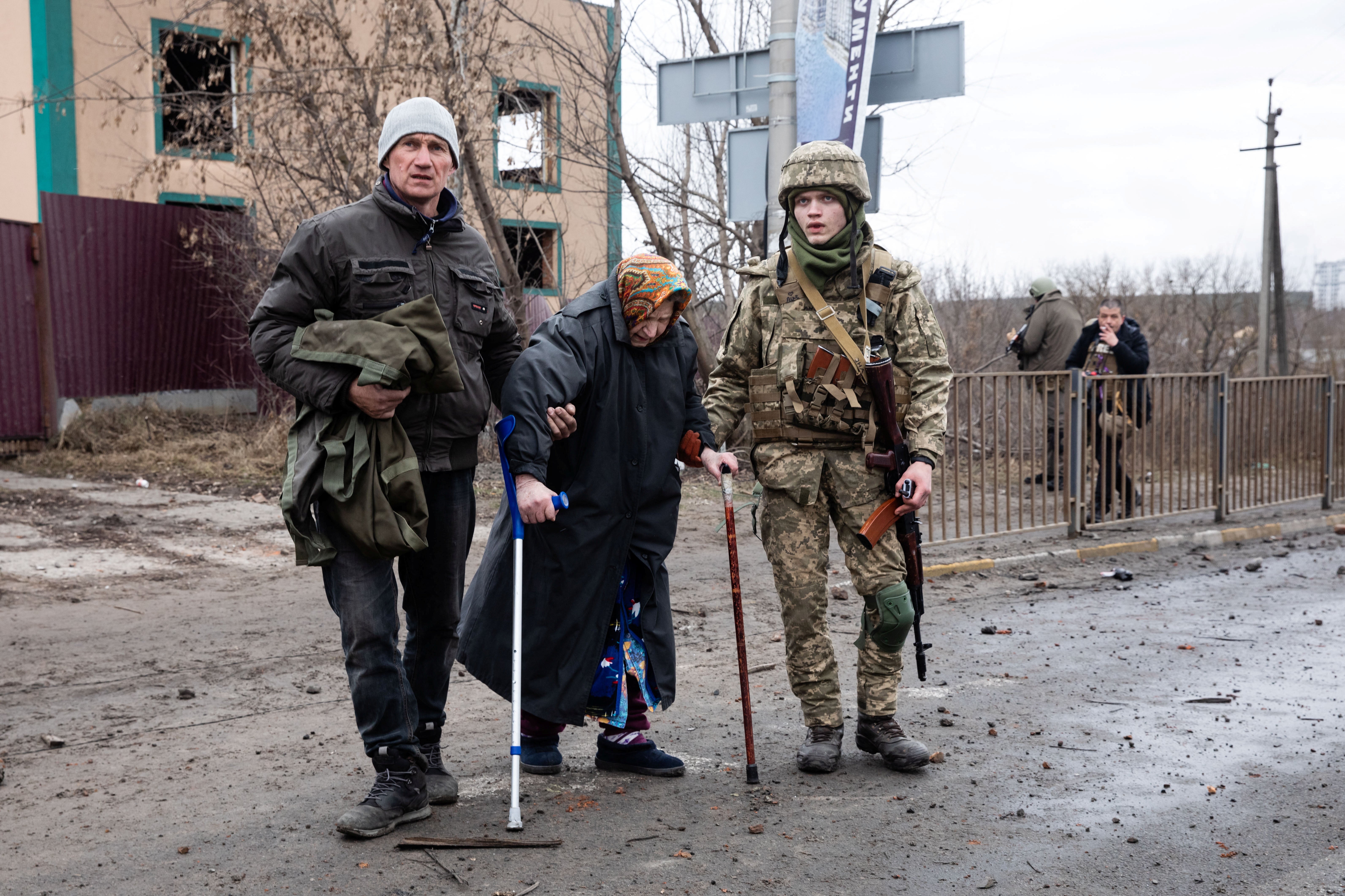 A Ukrainian service member assists an elderly woman in the town of Irpin in the Kyiv region, 5 March 2022