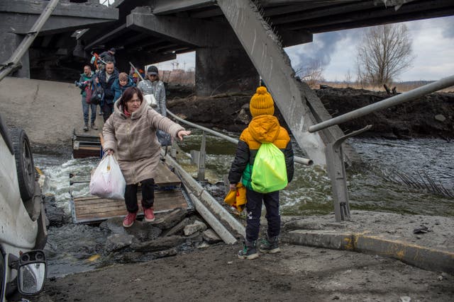 <p>Civilians cross amid rubble of a damaged bridge in Irpin on Sunday </p>