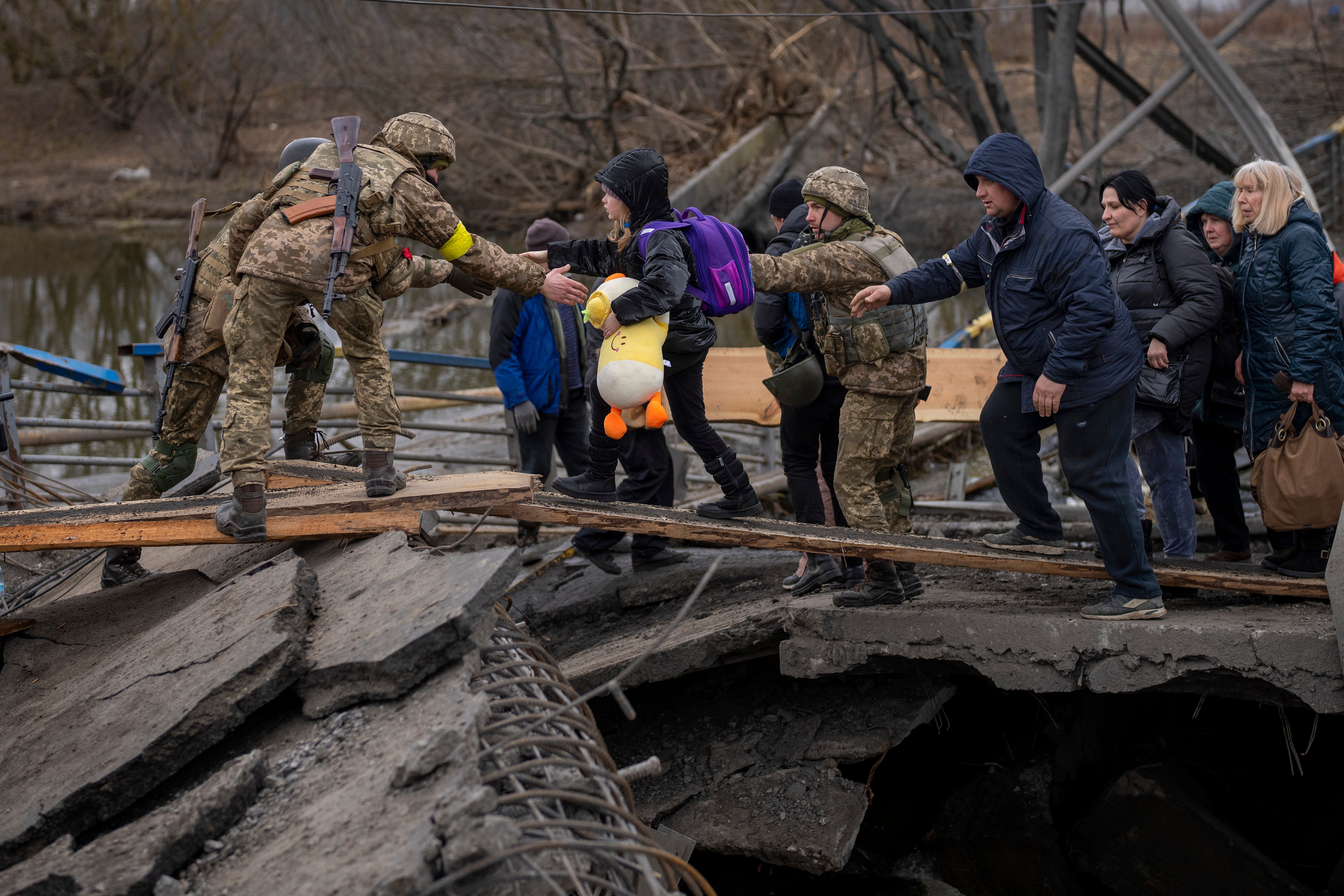 Ukrainian soldiers help a fleeing family to cross the Irpin river on the outskirts of Kyiv