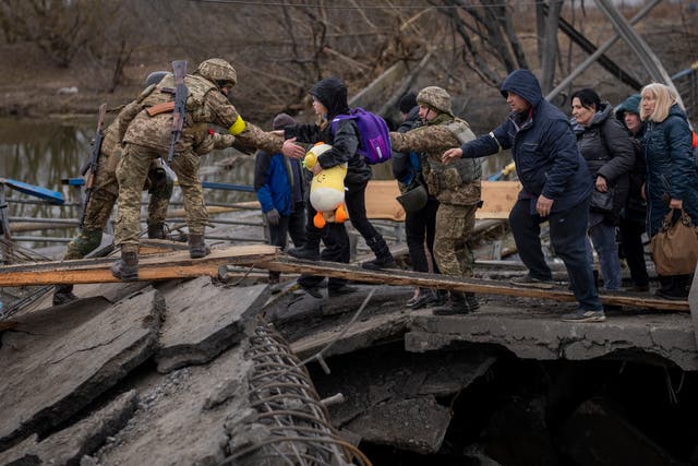 <p>Soldados ucranianos ayudan a una familia que huye a cruzar el río Irpin en las afueras de Kyiv</p>