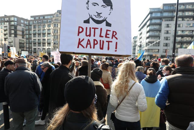 <p>A protester in Brussels carries a sign that shows a mash-up portrait of Putin and Hitler</p>