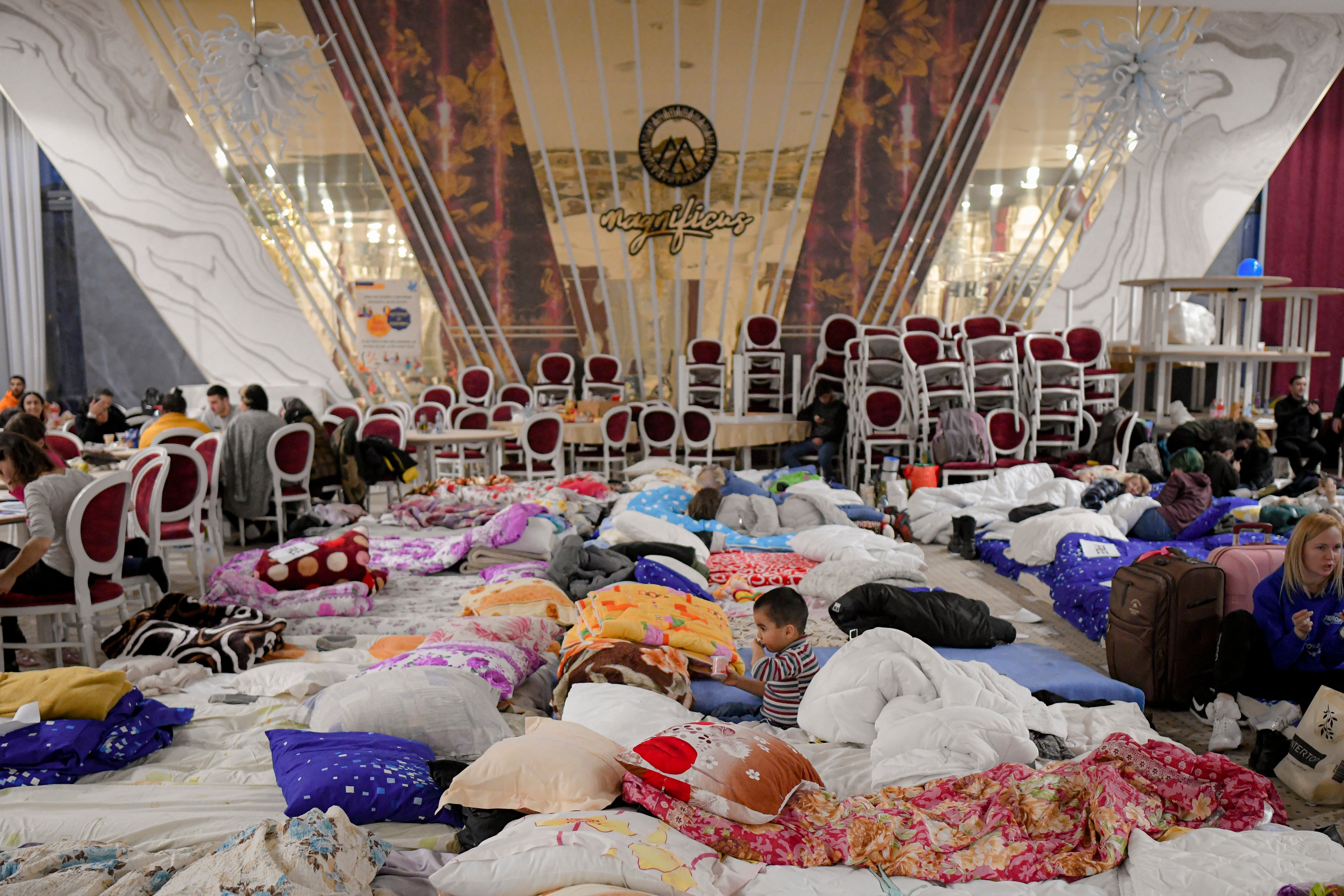 Refugees sit inside a ballroom converted into a makeshift refugee shelter in Suceava, Romania