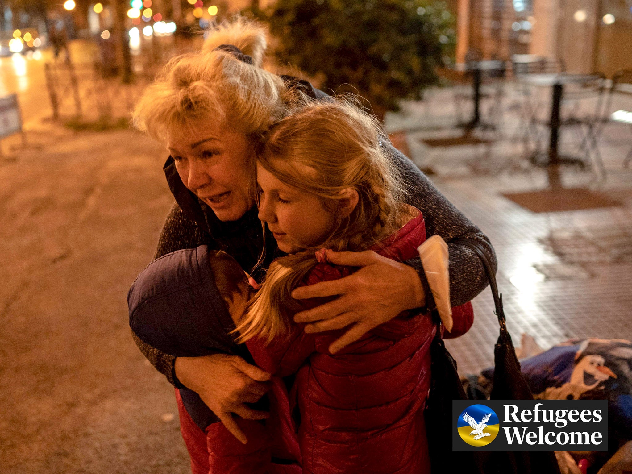 A Ukrainian refugee from Odesa hugs two children as they arrive in Athens by bus