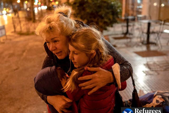 <p>A Ukrainian refugee from Odesa hugs two children as they arrive in Athens by bus </p>