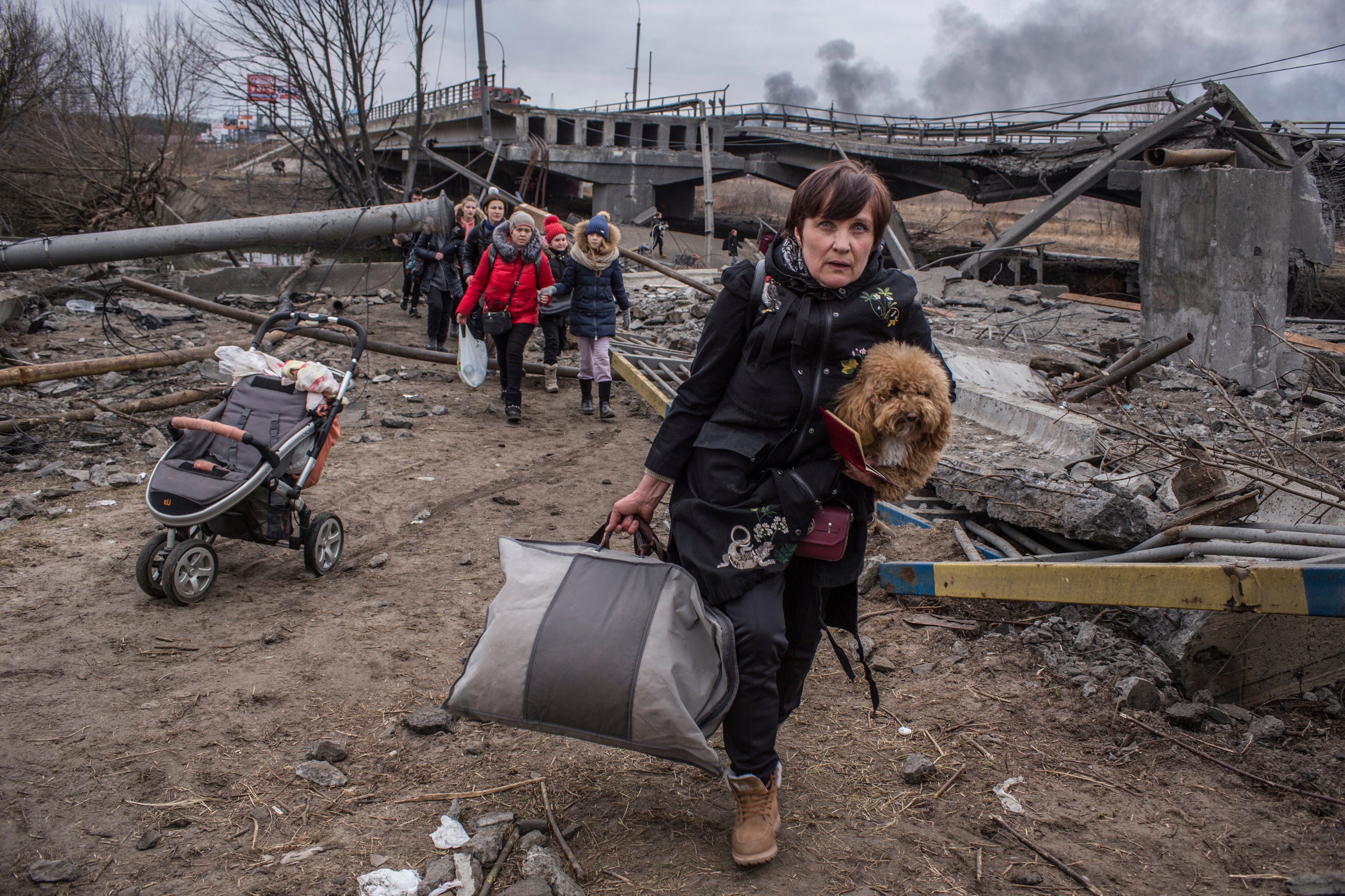 People cross an improvised path under a destroyed bridge while fleeing the town of Irpin.