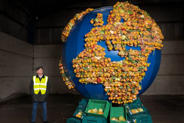 <p>Gregg Wallace poses next to an installation made from the food waste from a single UK household over a year</p>