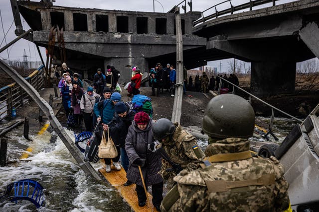 <p>Evacuees cross a destroyed bridge as they flee the city of Irpin, near Kyiv, on 7 March 2022</p>
