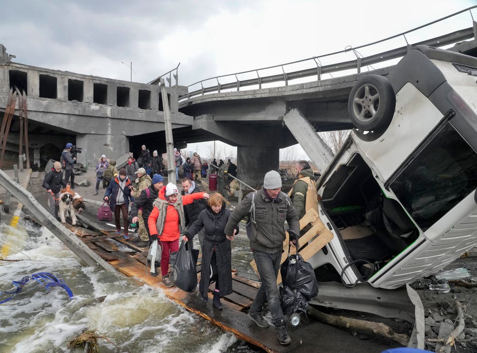 People cross an improvised path under a destroyed bridge while fleeing the town of Irpin close to Kyiv (Efrem Lukatsky/AP)